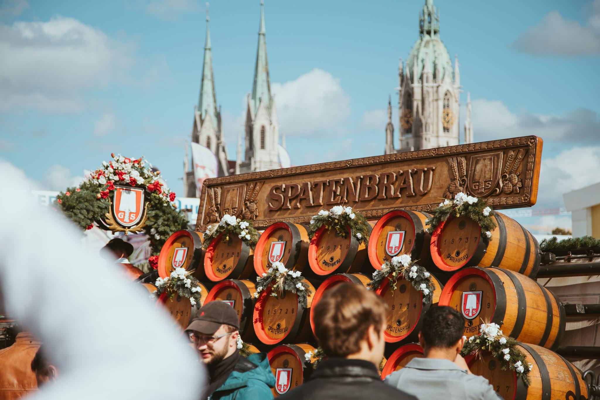 Vibrant Oktoberfest scene at Spatenbräu in München, featuring beer barrels and festival-goers under a clear sky.